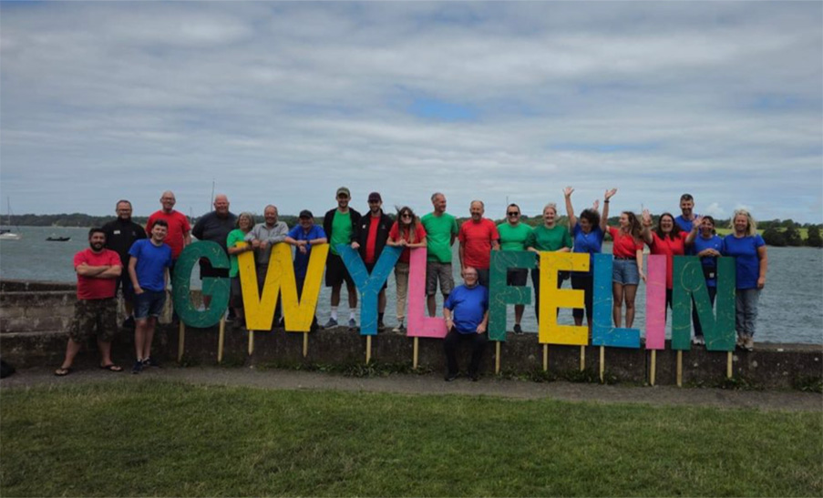 Staff behind the Gwyl Y Flein sign